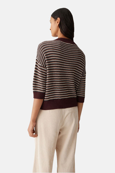 Pull à col rond marron par OPUS, avec motif à rayures horizontales, porté avec un pantalon beige en velours côtelé.