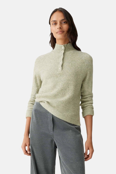 Groene gebreide trui van OPUS, gedragen met een geribbelde grijze broek, van achteren gezien.