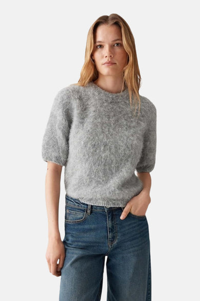 Pull gris à col rond de OPUS, avec des manches courtes bouffantes, porté avec un jean.
