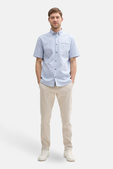 Blauw overhemd met korte mouwen van Tom Tailor, getextureerd, gedragen met een beige broek en witte sneakers.