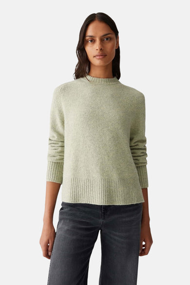 Pull à col rond vert d'OPUS, porté avec un jean sombre à coupe droite.
