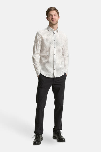 Chemise à manches longues blanche de Tom Tailor, à motifs discrets, portée avec un pantalon noir et des chaussures noires.