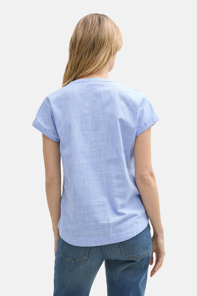 Blouse bleue à manches courtes de Tom Tailor, avec un motif tissé subtil et portée avec un jean.
