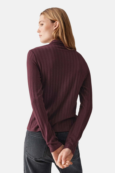 Gilet bordeaux à côtes, de OPUS, avec des manches longues et porté avec un jean.