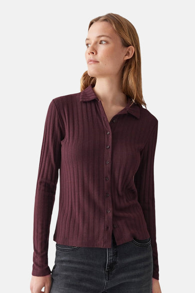 Gilet bordeaux côtelé de OPUS, avec manches longues et boutonné devant, porté avec un jean noir.