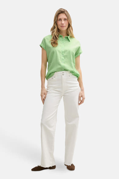 Chemisier vert à manches courtes de Tom Tailor, porté avec un jean blanc taille haute et des chaussures marron.