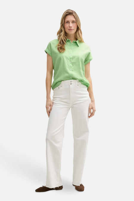 Chemisier vert à manches courtes de Tom Tailor, porté avec un jean blanc taille haute et des chaussures marron.