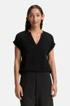 Blouse noire à manches courtes de Tom Tailor, avec un col en V, portée avec un pantalon noir.