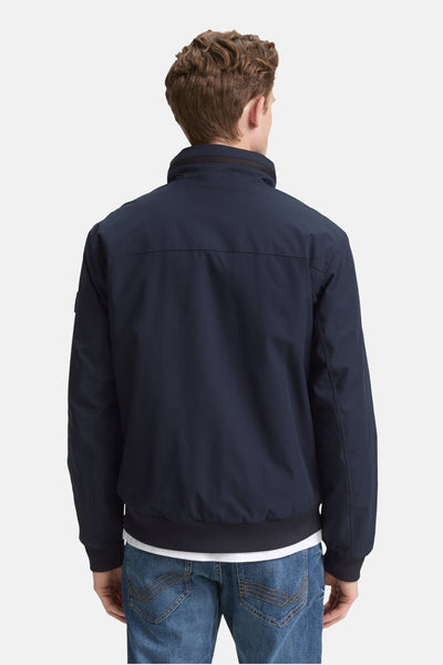 Veste courte bleu de Tom Tailor, vue de dos, portée avec un t-shirt blanc et un jean décontracté.