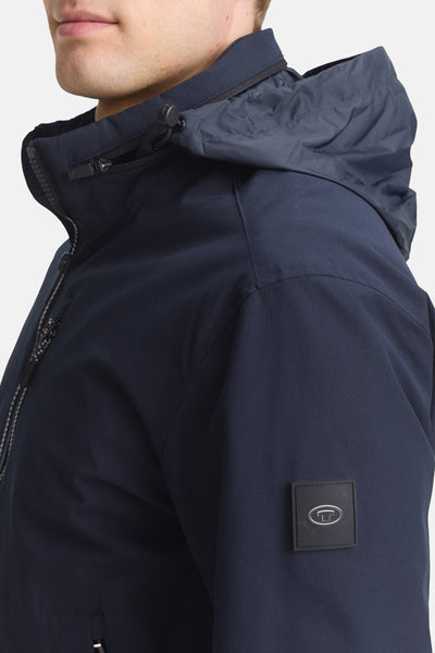 Veste courte bleue par Tom Tailor, avec capuche et fermeture éclair sur le devant.
