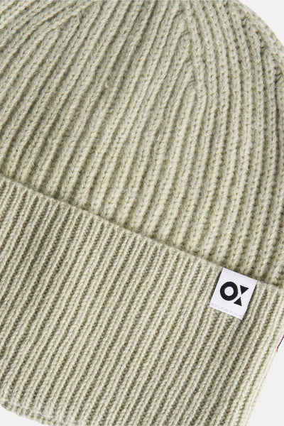 Bonnet vert en tricot fin de OPUS, avec un petit logo carré sur le bord plié.
