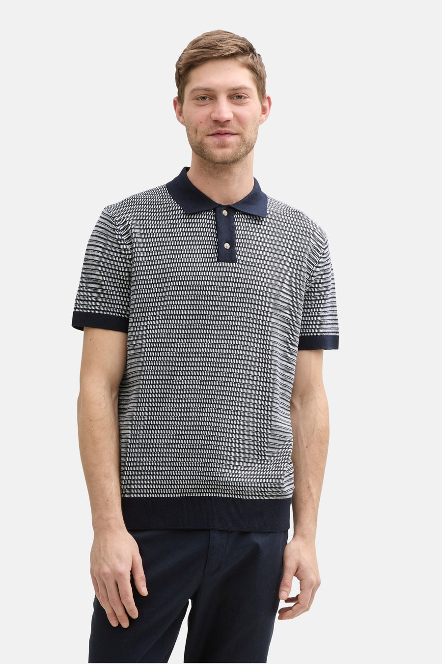 Blauwe Tom Tailor polo met textuurpatroon, gedragen met een donkere broek.