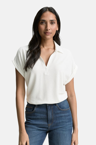 Wit poloshirt met korte mouwen van Tom Tailor, gedragen met een blauwe uitlopende spijkerbroek en zwarte sandalen.