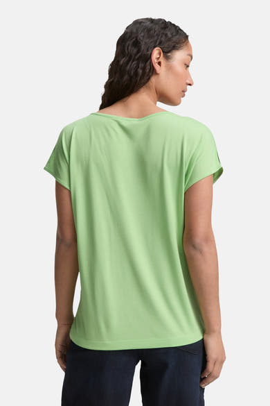 Blouse à manches courtes verte de Tom Tailor, vue de dos, portée avec un pantalon foncé.