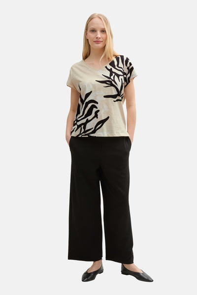 T-shirt à manches courtes beige par Tom Tailor avec imprimé zébré noir et pantalon noir ample.
