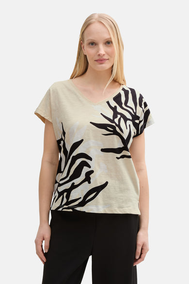 T-shirt à manches courtes beige de Tom Tailor avec motif abstrait noir et pantalon noir.
