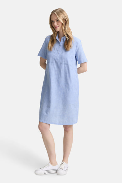 Korte blauwe jurk van Tom Tailor, met korte mouwen en borstzakken, gedragen met witte sneakers.