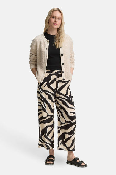 Pantalon multicolore Tom Tailor à motif zébré, porté avec un cardigan beige et des sandales noires.