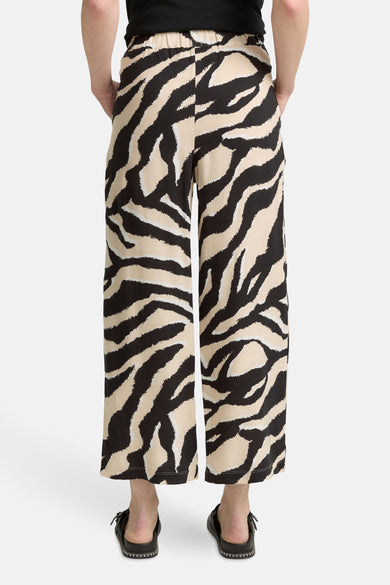 Pantalon multicolore à motif zèbre de Tom Tailor, coupe ample et fluide, porté avec des sandales noires.