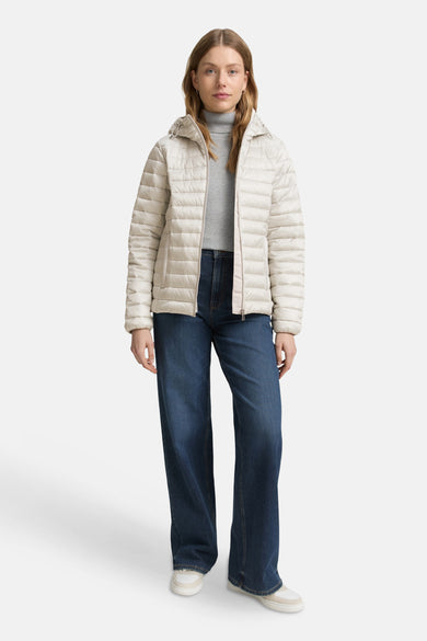 Veste courte grise par Tom Tailor, portée avec un col roulé gris, un jean bleu et des baskets blanches.