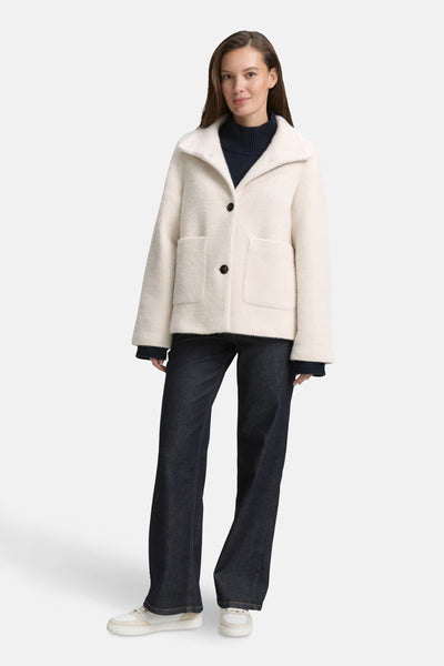 Veste courte beige de Tom Tailor, avec des poches plaquées et portée avec un pull bleu marine et un jean bootcut.