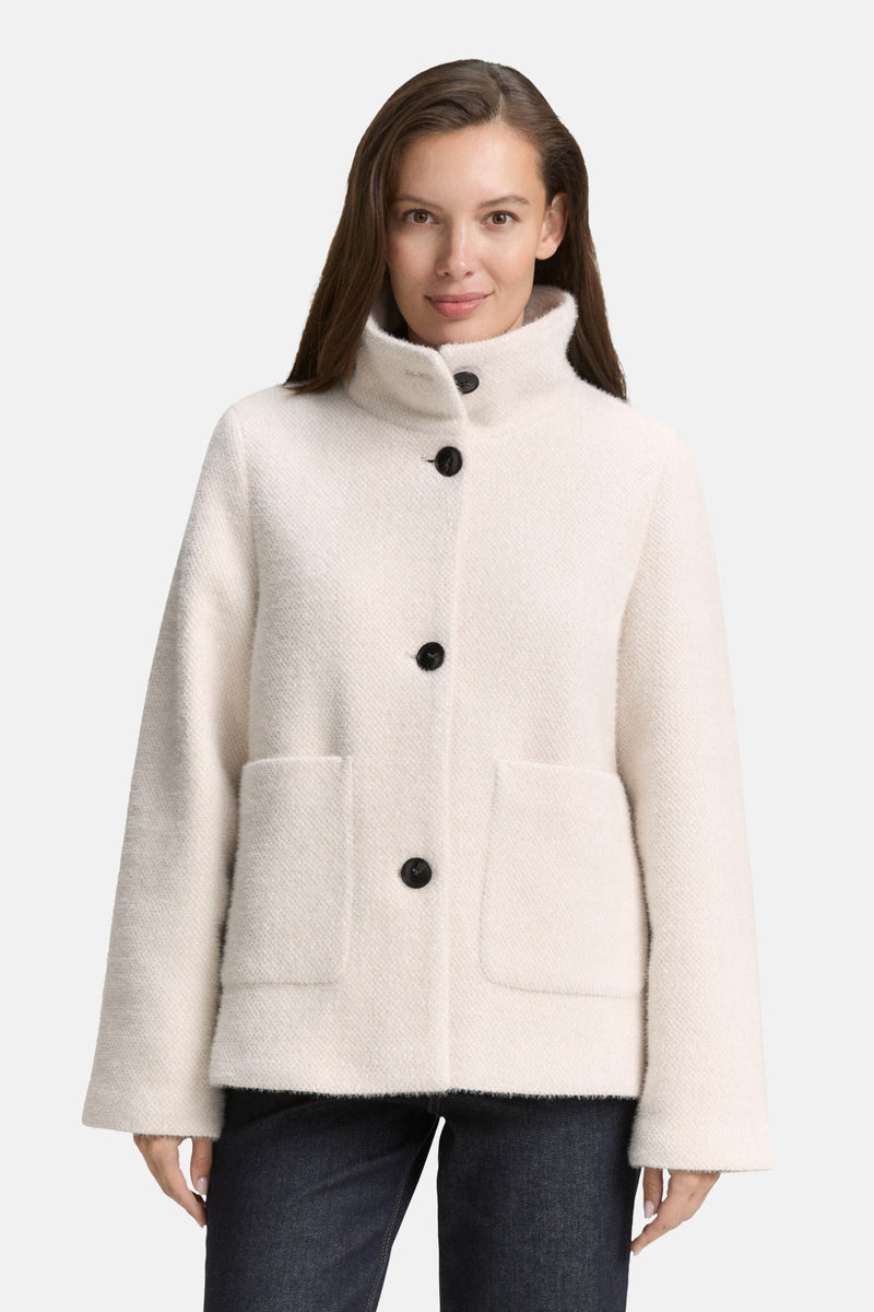Veste courte beige de Tom Tailor avec des poches plaquées et fermeture boutonnée noire, portée avec un jean foncé.

