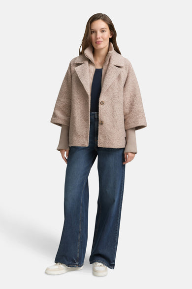Veste courte beige de Tom Tailor, portée avec un haut bleu marine et un jean large.
