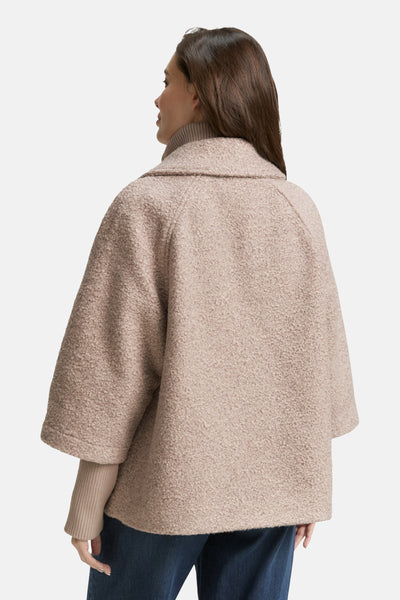 Veste courte beige de Tom Tailor, texture bouclée, manches trois quarts, portée avec un pull col roulé uni.