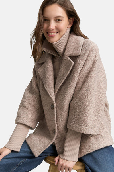 Veste courte beige de Tom Tailor, texturée, avec un col montant et portée sur un pull beige et un jean bleu.