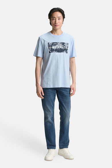 Blauw T-shirt met korte mouwen van Tom Tailor, met grafische print voor, gedragen met een spijkerbroek en witte sneakers.