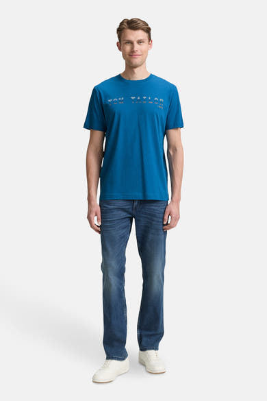 Blauw T-shirt met korte mouwen van Tom Tailor, gedragen met een spijkerbroek en witte sneakers.