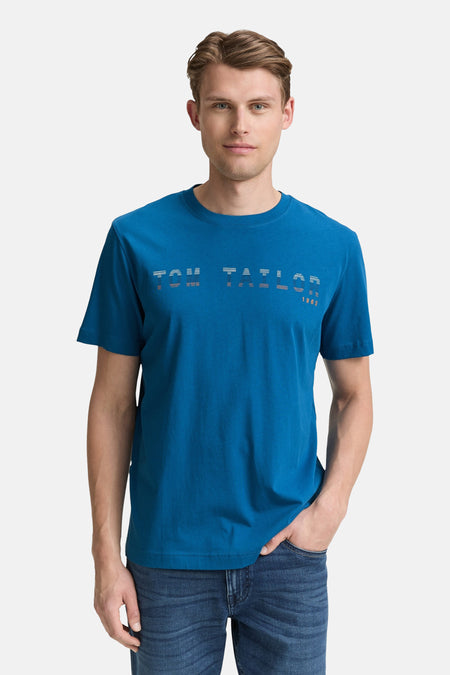 Blauw T-shirt met korte mouwen van Tom Tailor, met decoratieve opdruk op de voorkant en gedragen met een spijkerbroek.