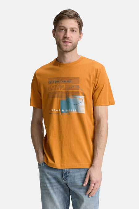 Okerkleurig T-shirt met korte mouwen van Tom Tailor, met een grafische print op de voorkant, gedragen met een blauwe jeans.