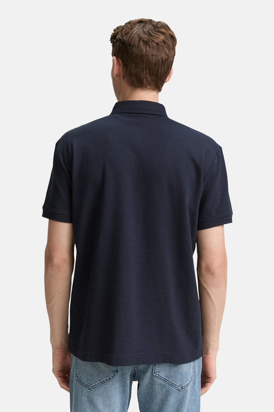 Donkerblauwe polo met korte mouwen van Tom Tailor, met een wafelstructuur en gedragen met een spijkerbroek.