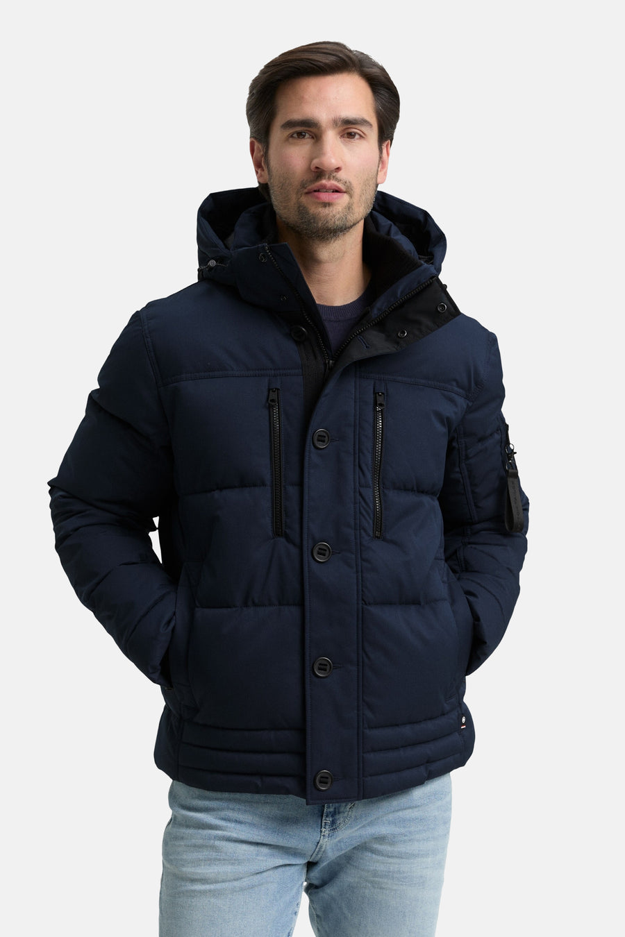 Veste courte bleue de Tom Tailor avec capuche et poches, portée avec un jean clair.
