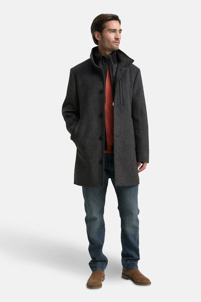 Grijze jas van Tom Tailor, met zakken en gedragen over een oranje trui en een blauwe jeans.