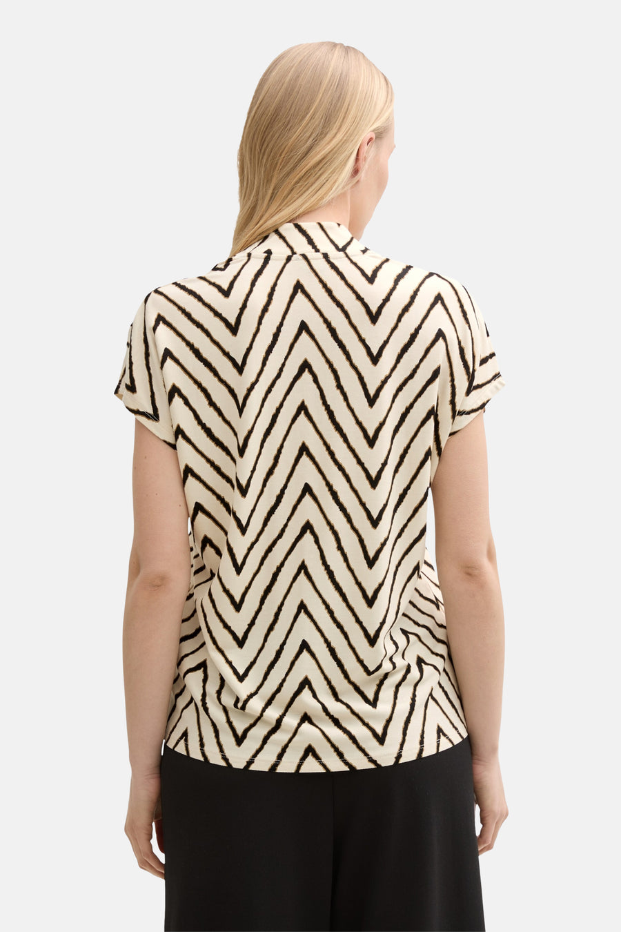 Blouse à manches courtes multicolore de Tom Tailor avec motif en chevron noir, portée avec un pantalon noir.