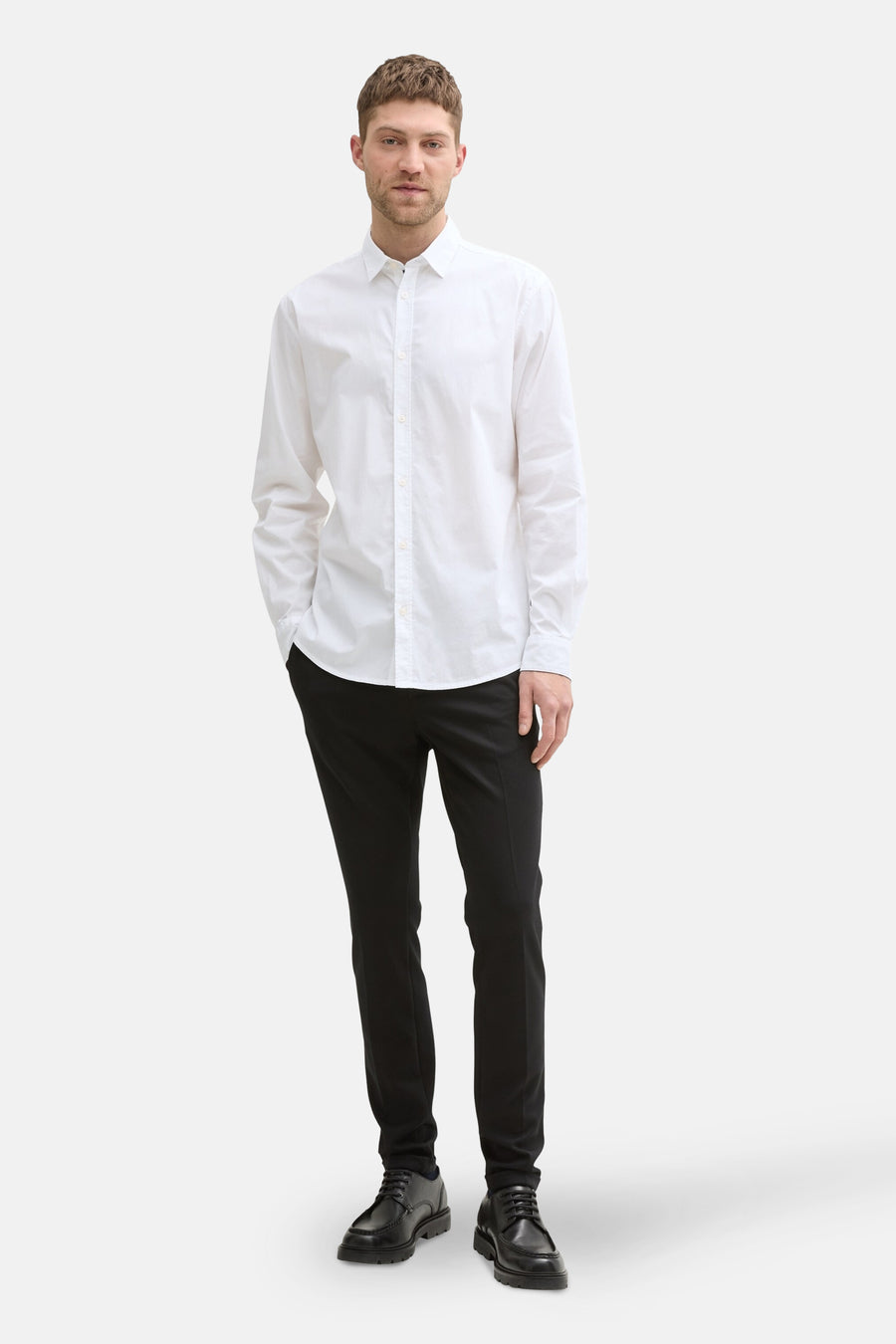 Chemise à manches longues blanche de Tom Tailor, portée avec un pantalon noir et des chaussures en cuir.