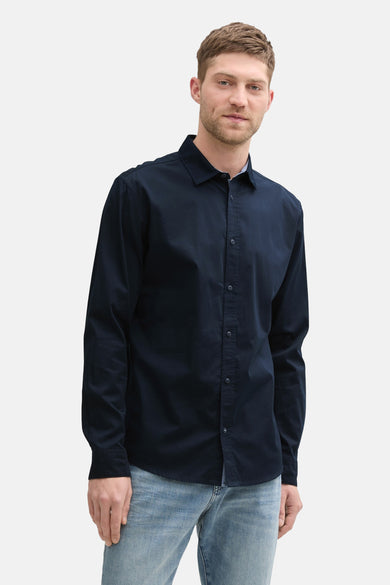 Donkerblauwe blouse met lange mouwen van Tom Tailor, gedragen met een lichte spijkerbroek en zwarte leren schoenen.