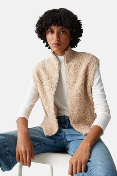 Pull écru à col rond de OPUS, porté avec un gilet beige texturé et un jean bleu clair.
