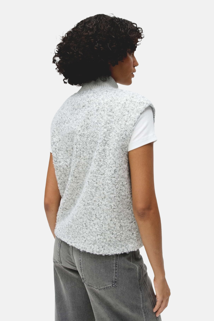 Vue de dos d’une femme portant un cardigan gris clair texturé OPUS sur un t-shirt blanc et un jean gris.