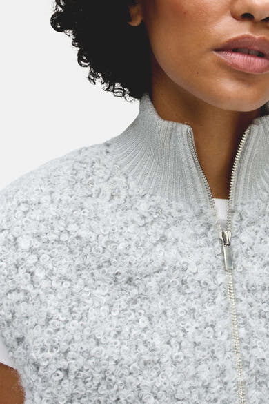 Gros plan d’un cardigan gris OPUS à col montant et fermeture zippée, porté par un mannequin.