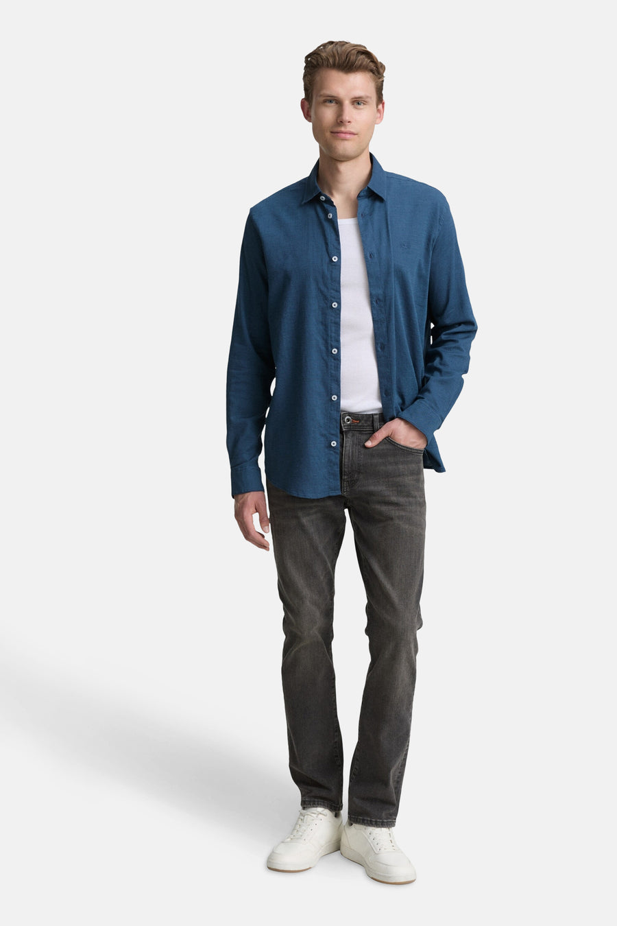 Blauw overhemd met lange mouwen van Tom Tailor, gedragen over een wit T-shirt, met een grijze jeans.