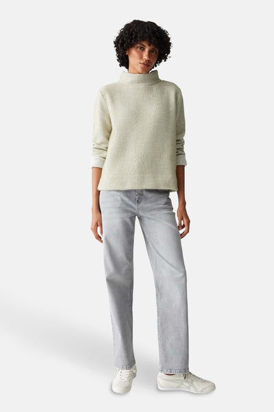 Pull vert texturé de OPUS, porté avec un jean gris et des baskets blanches.
