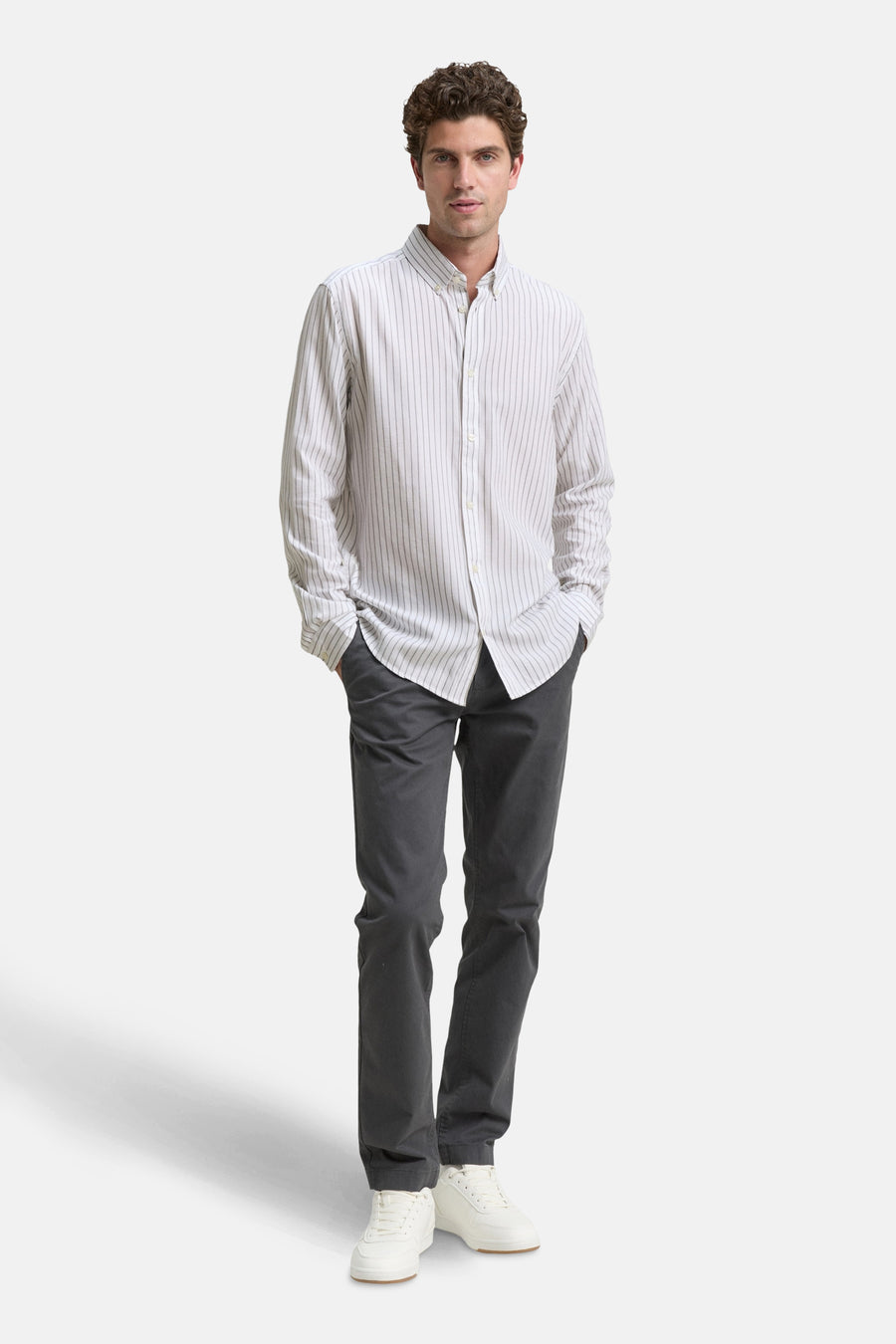 Wit overhemd met lange mouwen en verticale strepen, van Tom Tailor, gedragen met een grijze broek en witte sneakers.