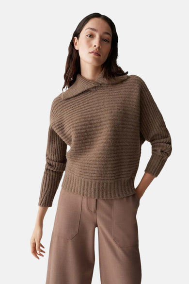 Pull brun à col châle de OPUS, en maille côtelée, porté avec un pantalon taille haute marron.
