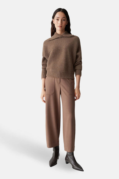 Pull brun à col châle par OPUS, en tricot côtelé, porté avec un pantalon marron et des bottines en cuir.