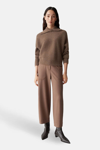 Pull brun à col châle par OPUS, en tricot côtelé, porté avec un pantalon marron et des bottines en cuir.