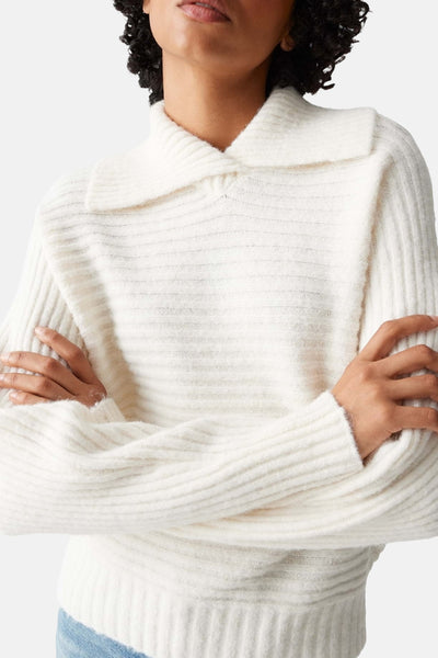 Pull beige à col rabattu, par OPUS, avec texture côtelée horizontale et manches longues, porté avec un jean.