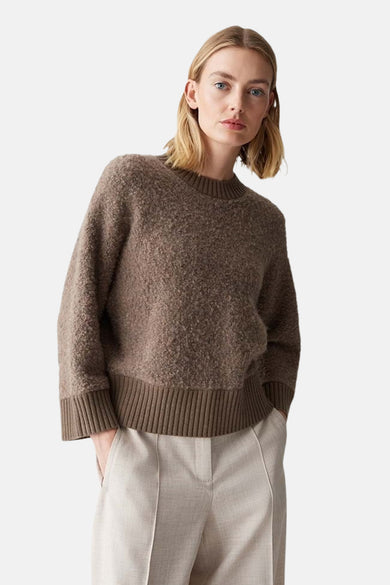 Pull à col rond marron de OPUS, avec une texture douce et porté avec un pantalon beige.